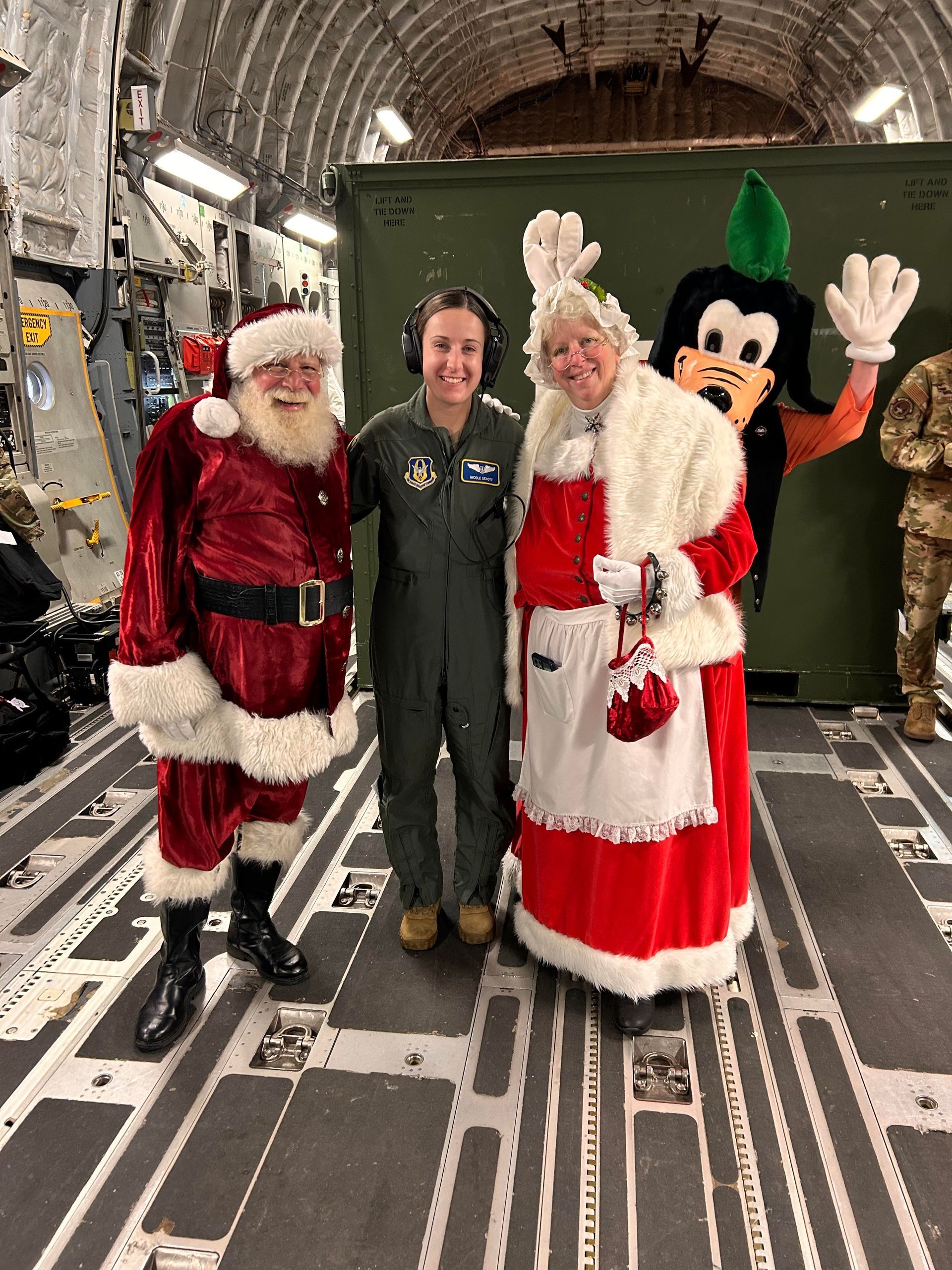 A group of people dressed as santa claus and mrs. claus are posing for a picture on a plane.