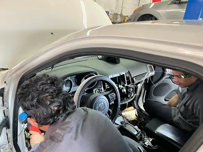 A man is working on the interior of a car in a garage.