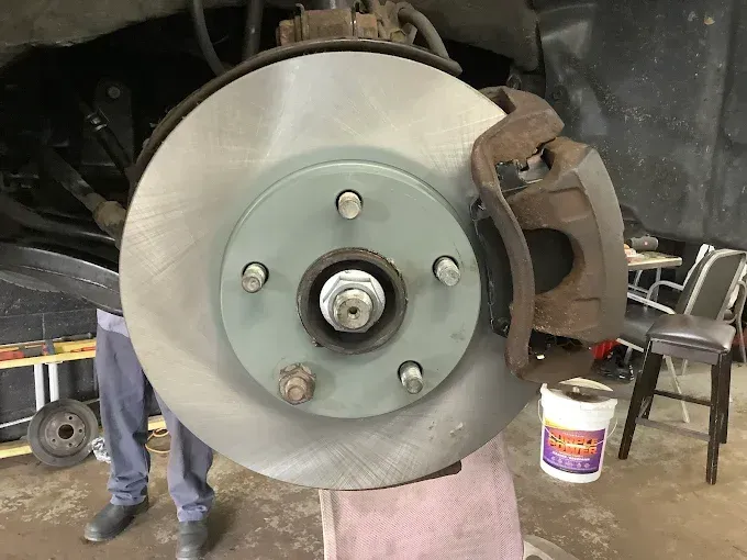 A brake disc is being removed from a car in a garage.