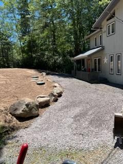 A large white house with a gravel driveway in front of it.