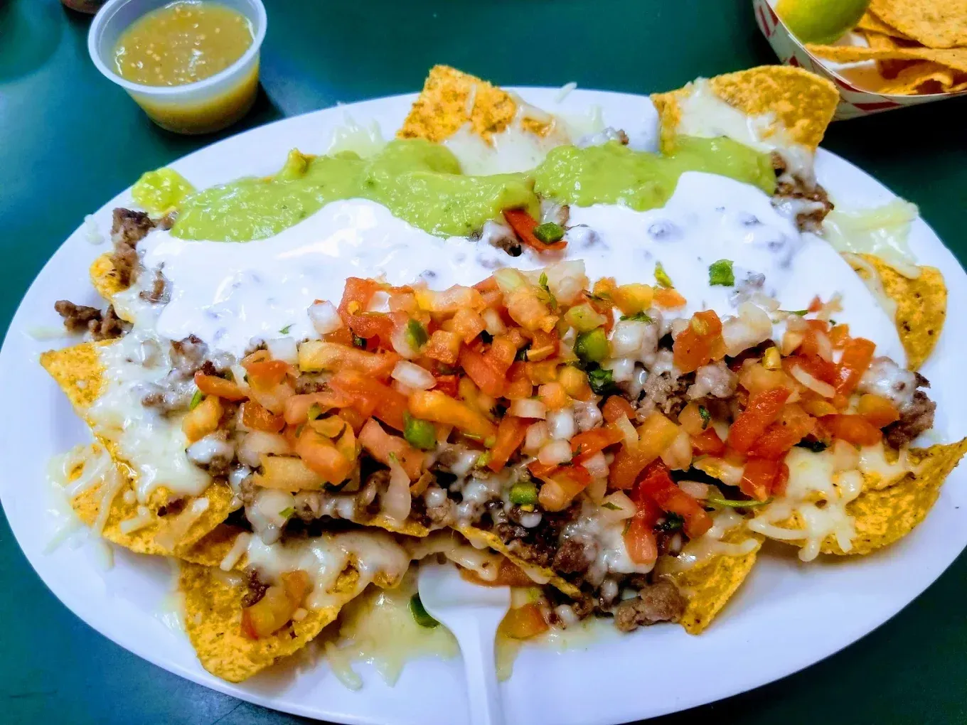 A plate of nachos with guacamole and sour cream on top