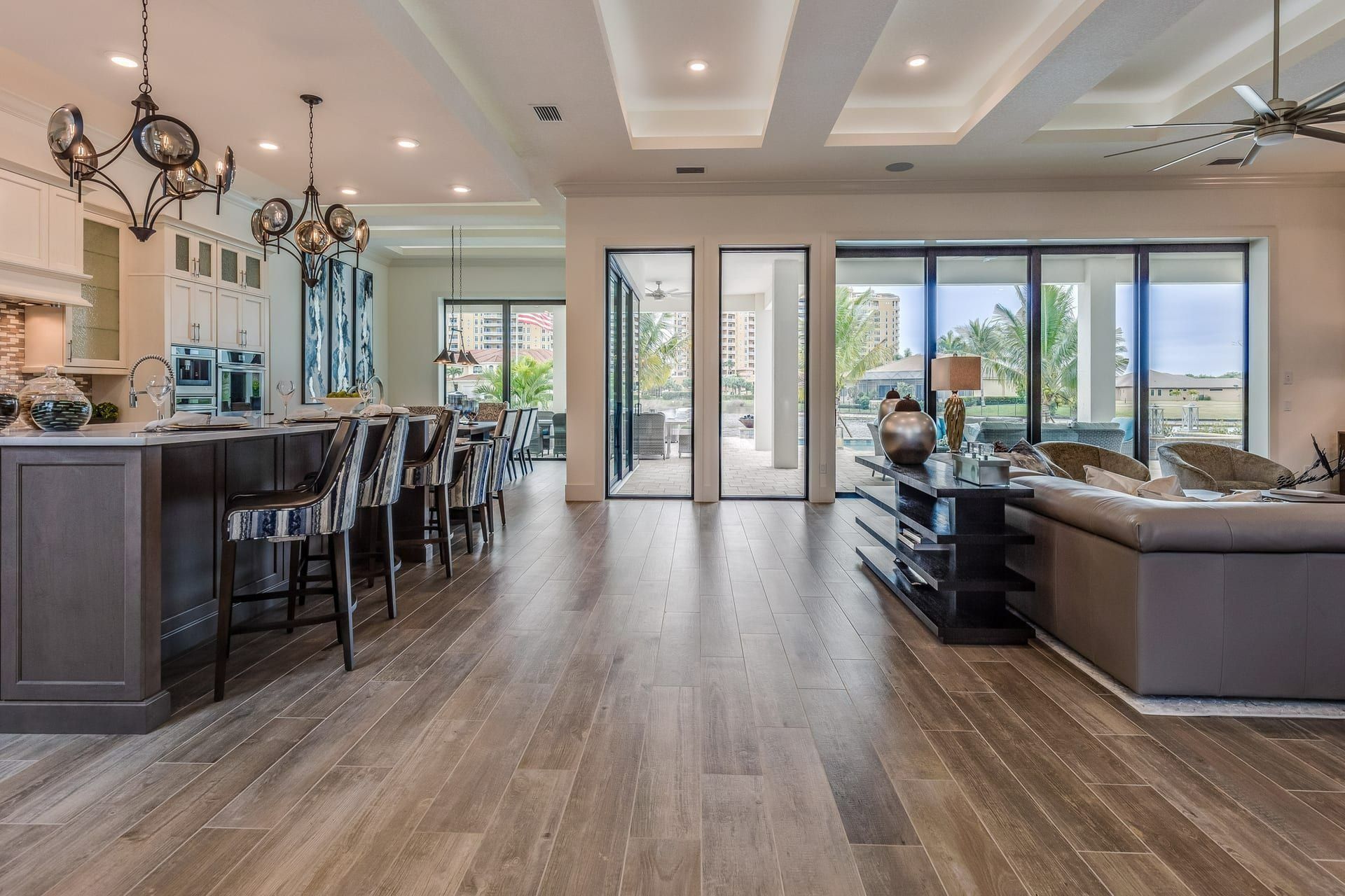 Spacious modern living space with kitchen island, dark wood floors, and large glass doors.