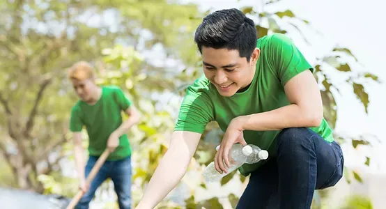 A man in a green shirt is kneeling down while holding a bottle of water.