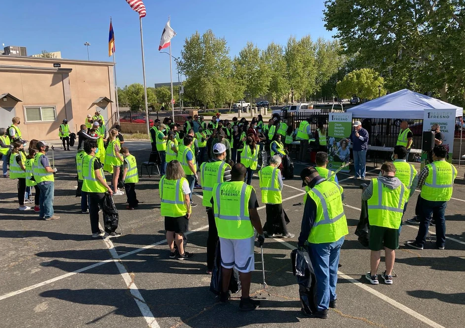 A group of people wearing neon yellow vests are standing in a parking lot.