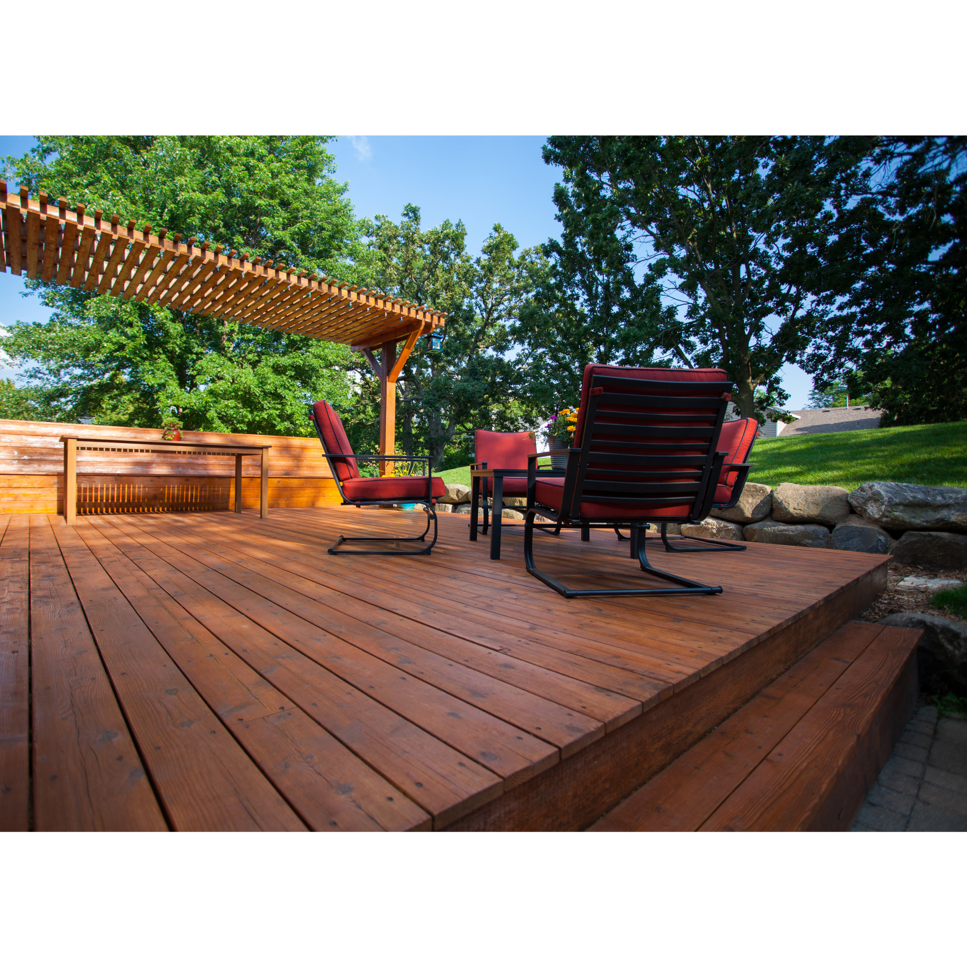 A wooden deck with a pergola and chairs on it