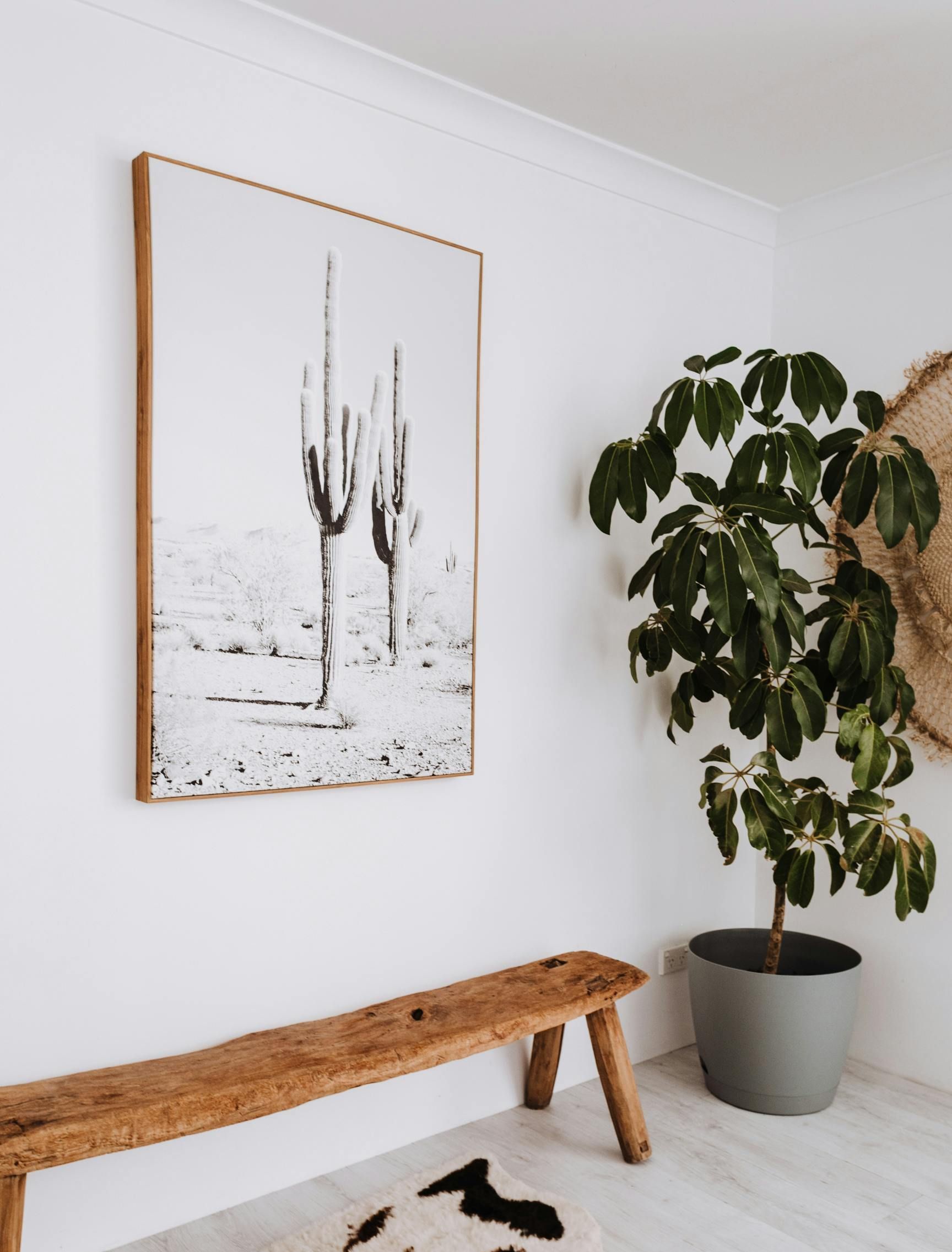 A painting of cactus is hanging on a wall above a wooden bench in Utah