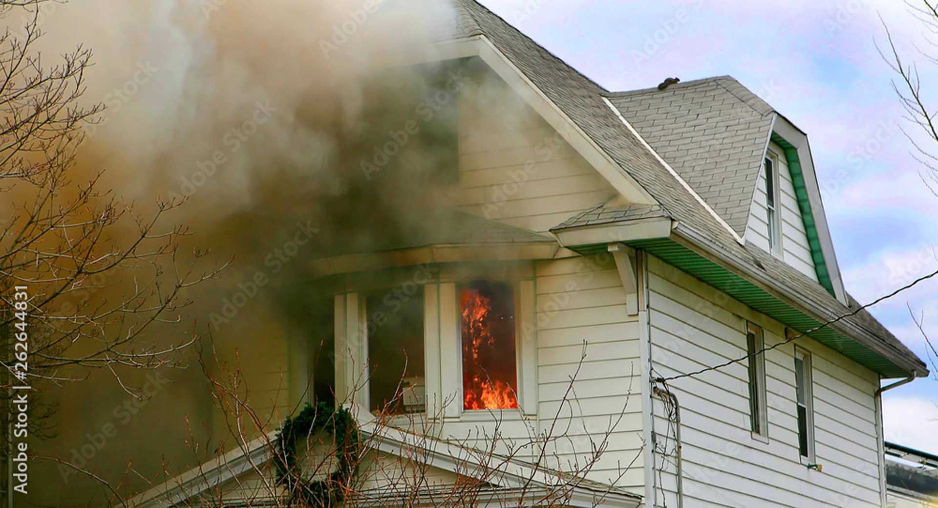 House engulfed in flames, smoke billowing from windows.
