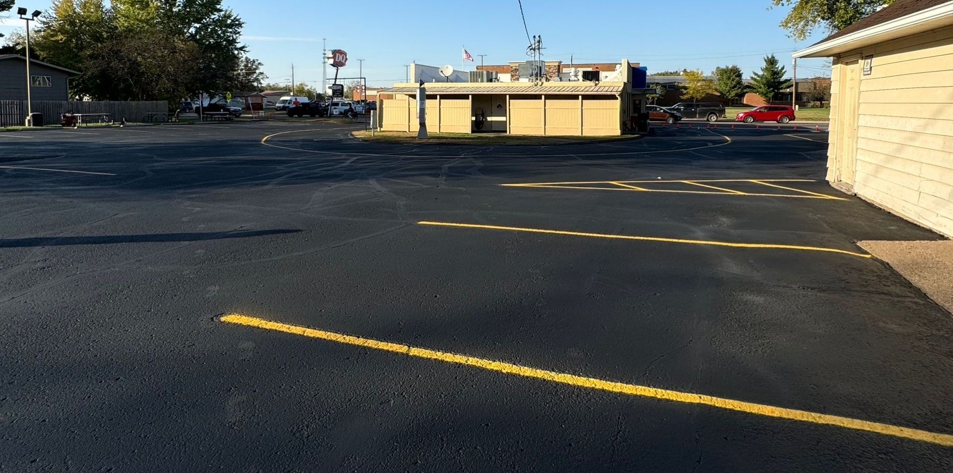 A parking lot with a yellow line and a building in the background.