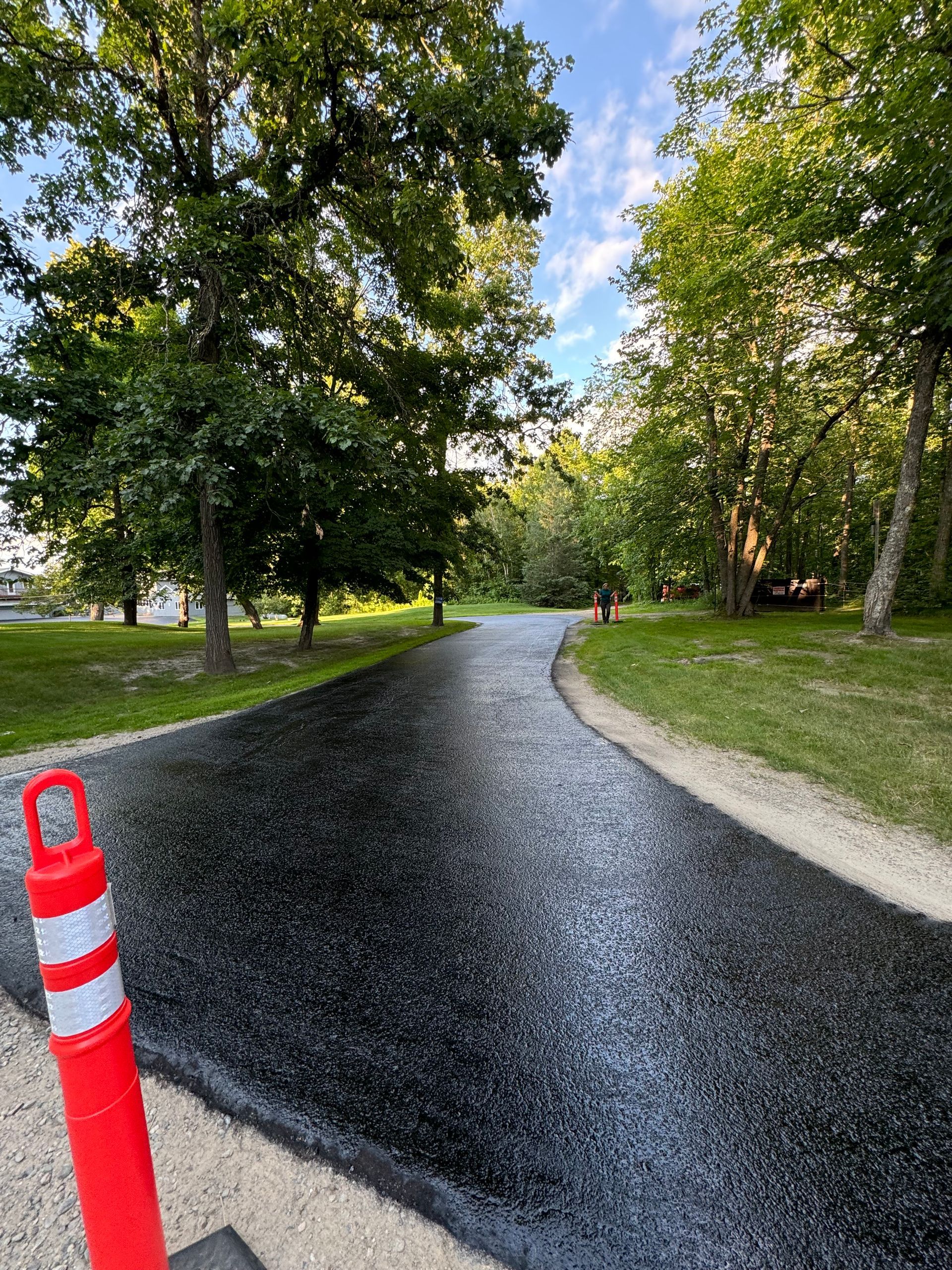 A red and white traffic cone is sitting on the side of a road.