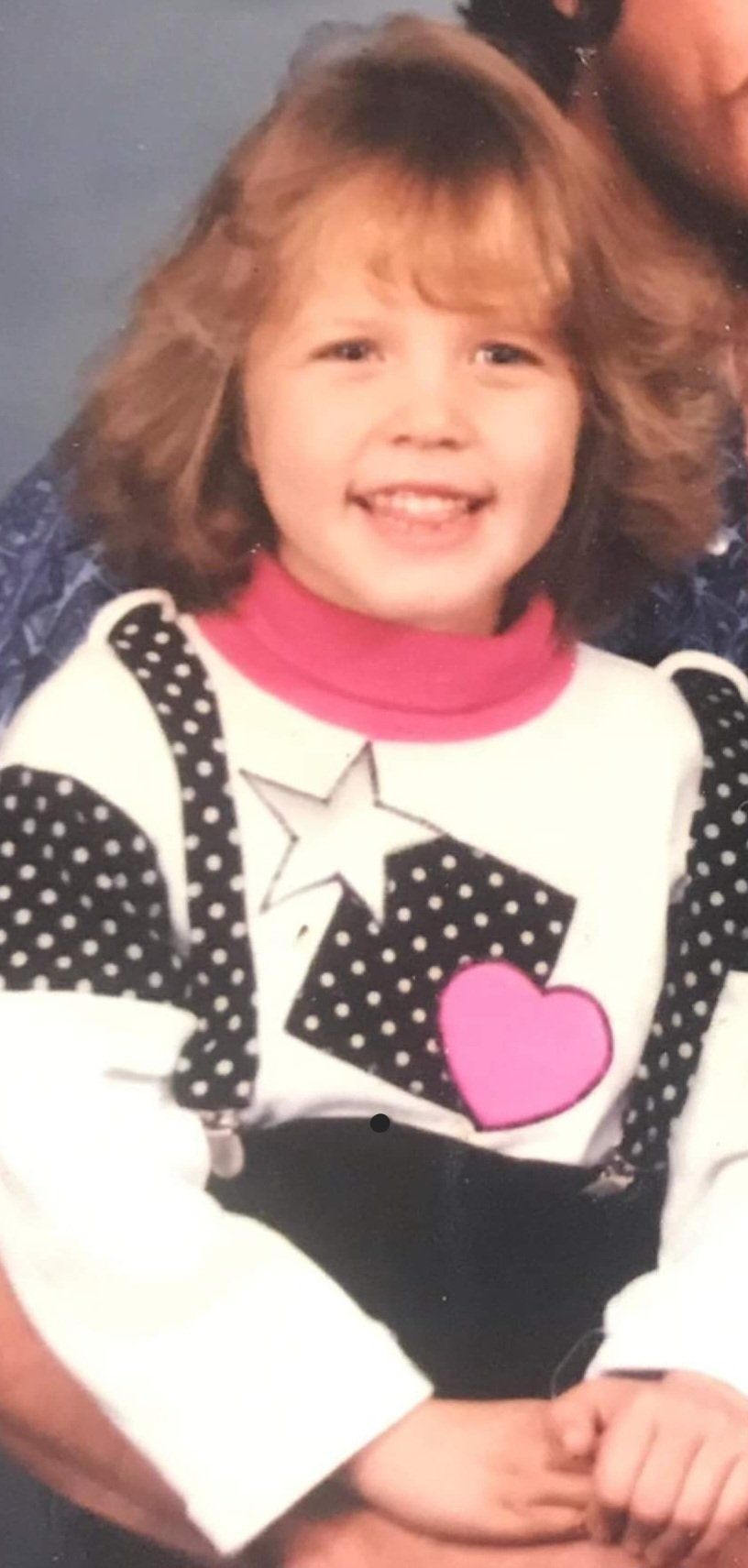 A little girl wearing a sweater with a pink heart on it