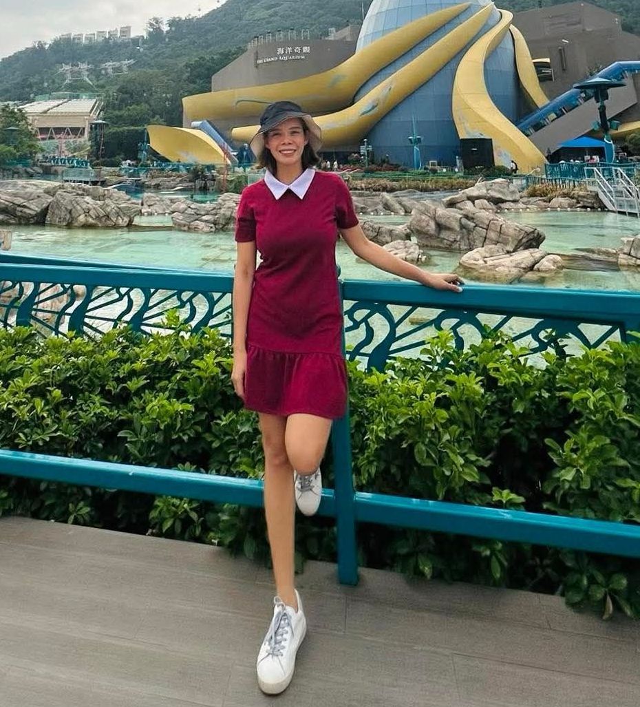 A woman in a red dress is standing next to a fence