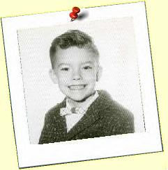 A black and white photo of a young boy in a suit and bow tie.