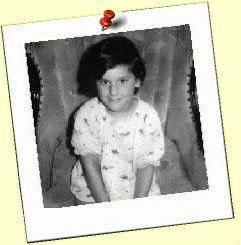 A black and white photo of a little girl is pinned to a wall.