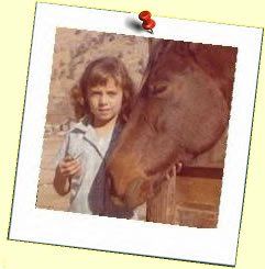 A young girl is standing next to a brown horse.