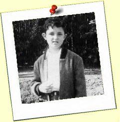 A black and white photo of a young boy is pinned to a wall.