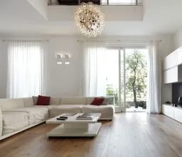 White lounge room with timber floor and white couch, white coffee table and sheet white curtains.