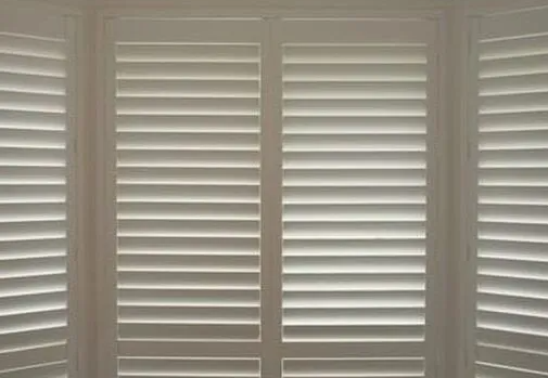 Close up of white closed PVC Plantation Shutters, with light filtering in.