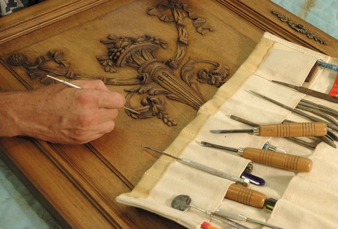 Persona che intaglia il legno con degli attrezzi.