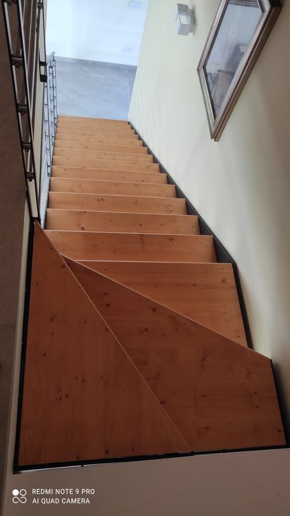 Scala in legno con illuminazione calda, corrimano in metallo.