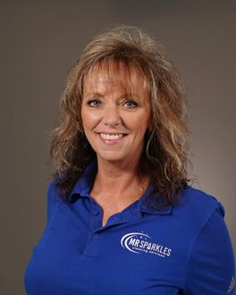 A woman in a blue shirt is smiling for the camera.