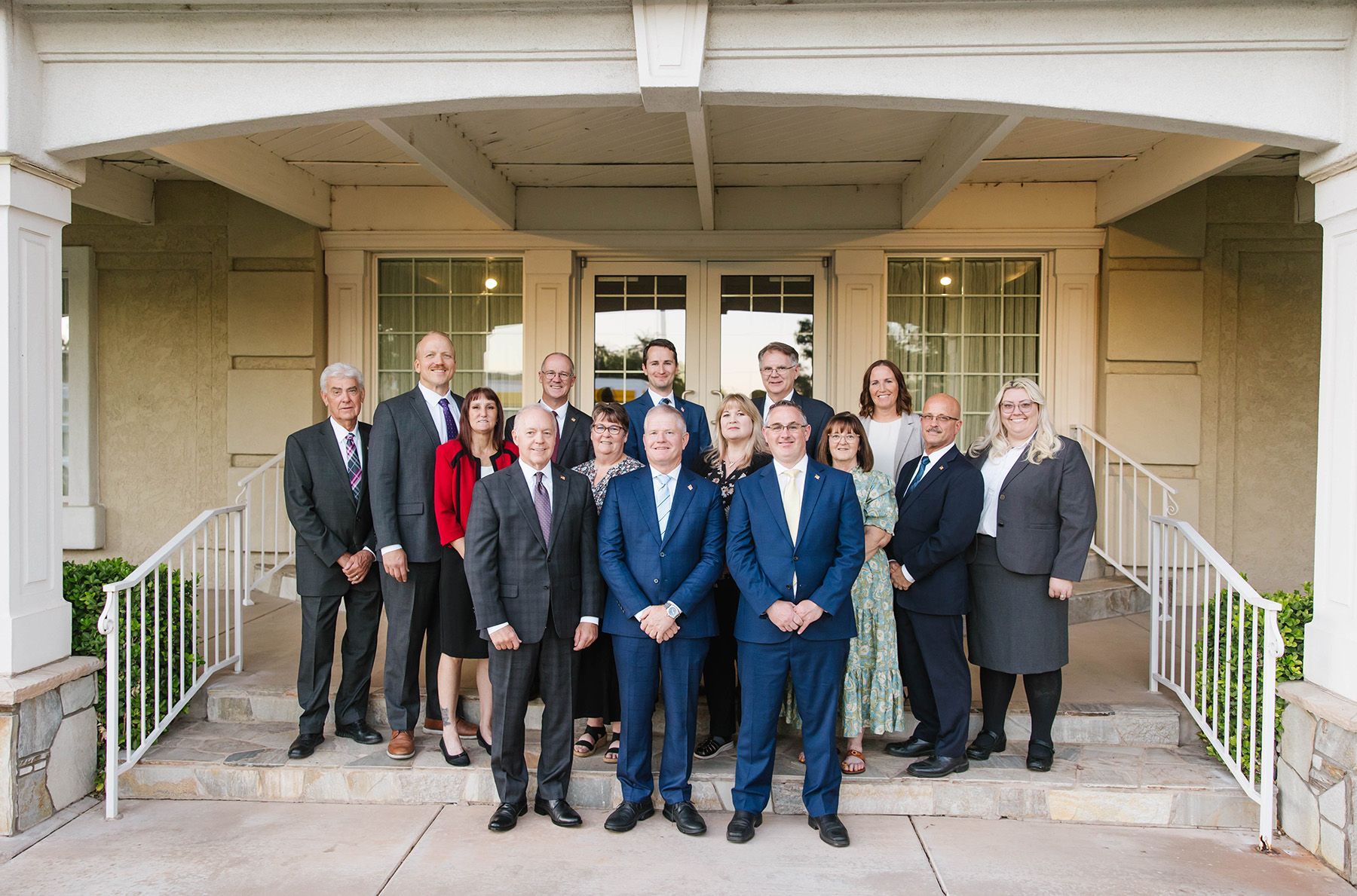 Group of people posing for photo on steps in front of a building with white columns.