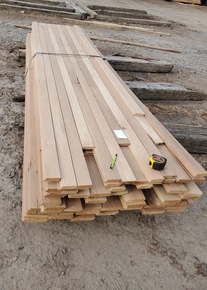 Stack of light brown wooden floorboards, with a tape measure and pencil on top.