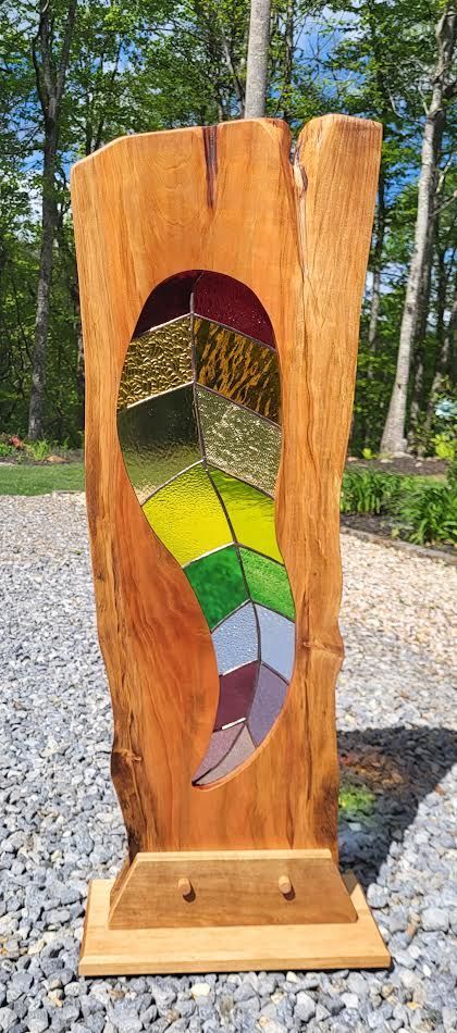 Wooden art sculpture with a colorful stained-glass feather inset.