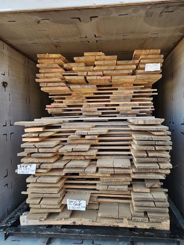 Stack of weathered wooden planks inside a structure, possibly a kiln.
