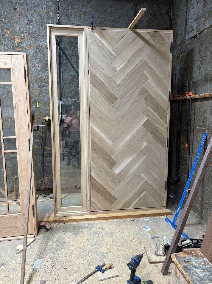 Herringbone wooden door and sidelight being assembled in a workshop.