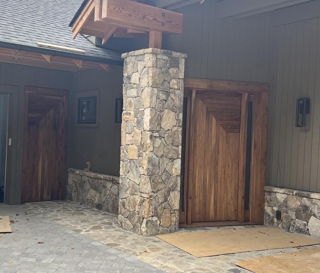 Exterior of building with stone column and wooden doors.