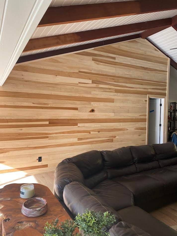 Wood-paneled wall and ceiling with a brown leather sectional sofa and wooden table.