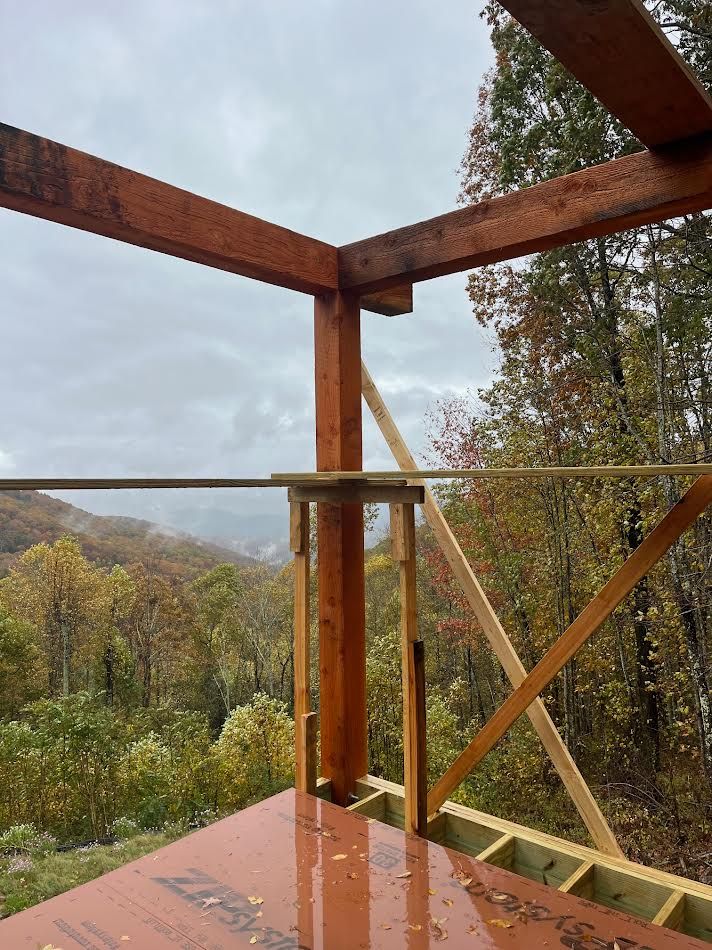 Wooden beams of a structure under construction, with a view of a mountain landscape.