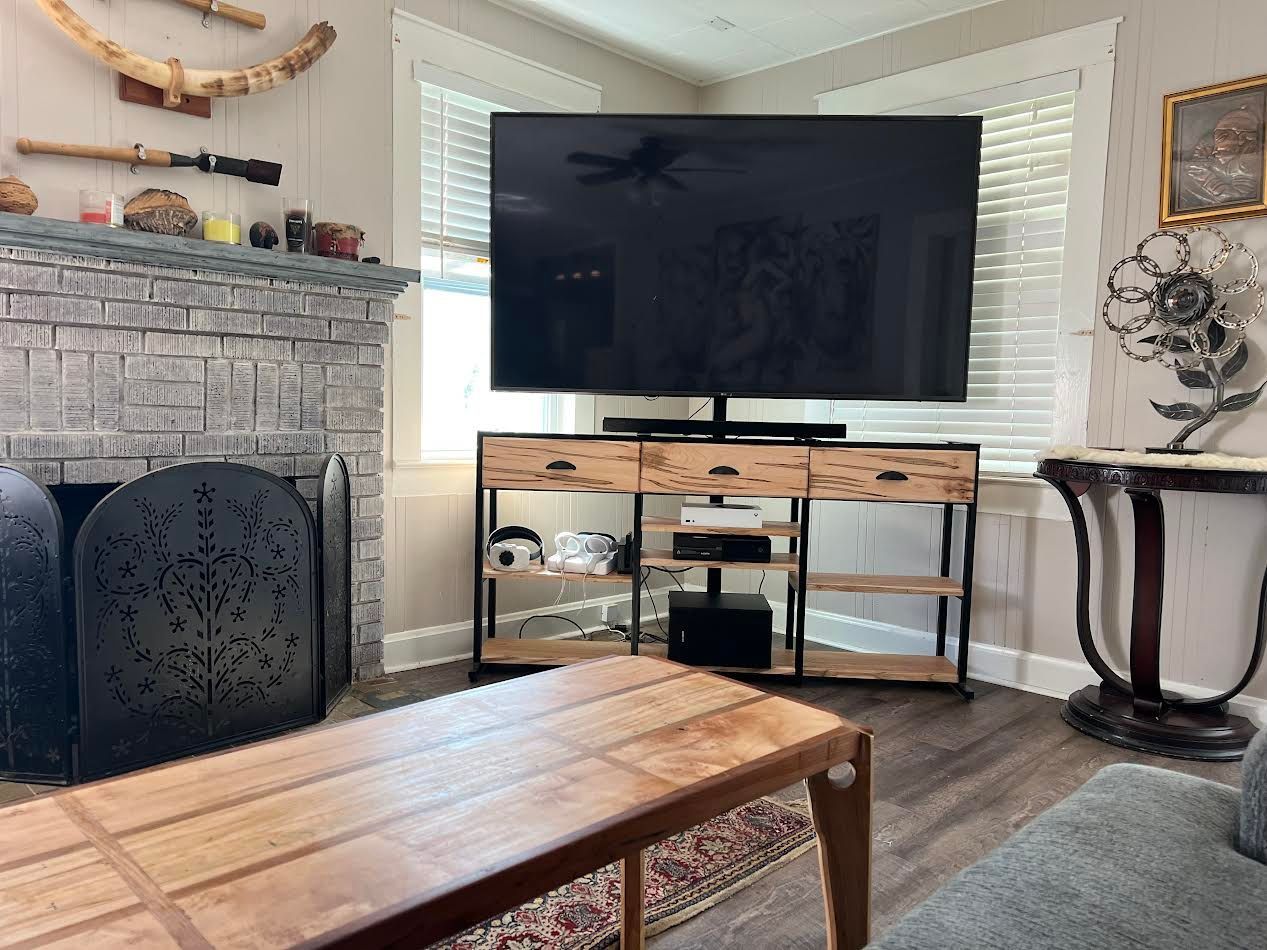 Living room with TV on a wooden console, fireplace, and coffee table.