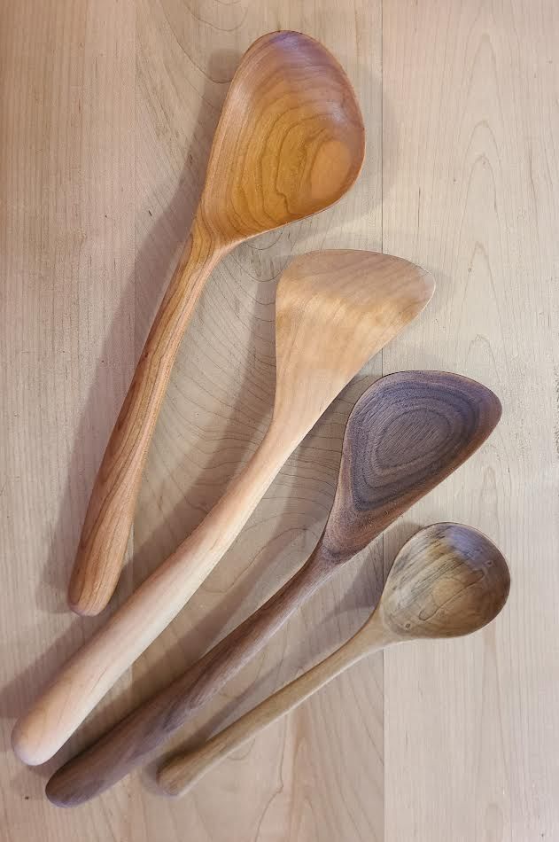 Four wooden spoons of varying sizes on a wood surface.