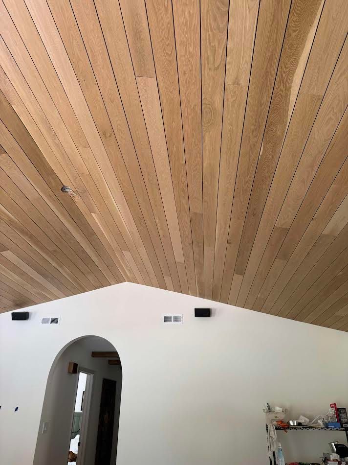 Wooden plank ceiling with a white arched wall below.