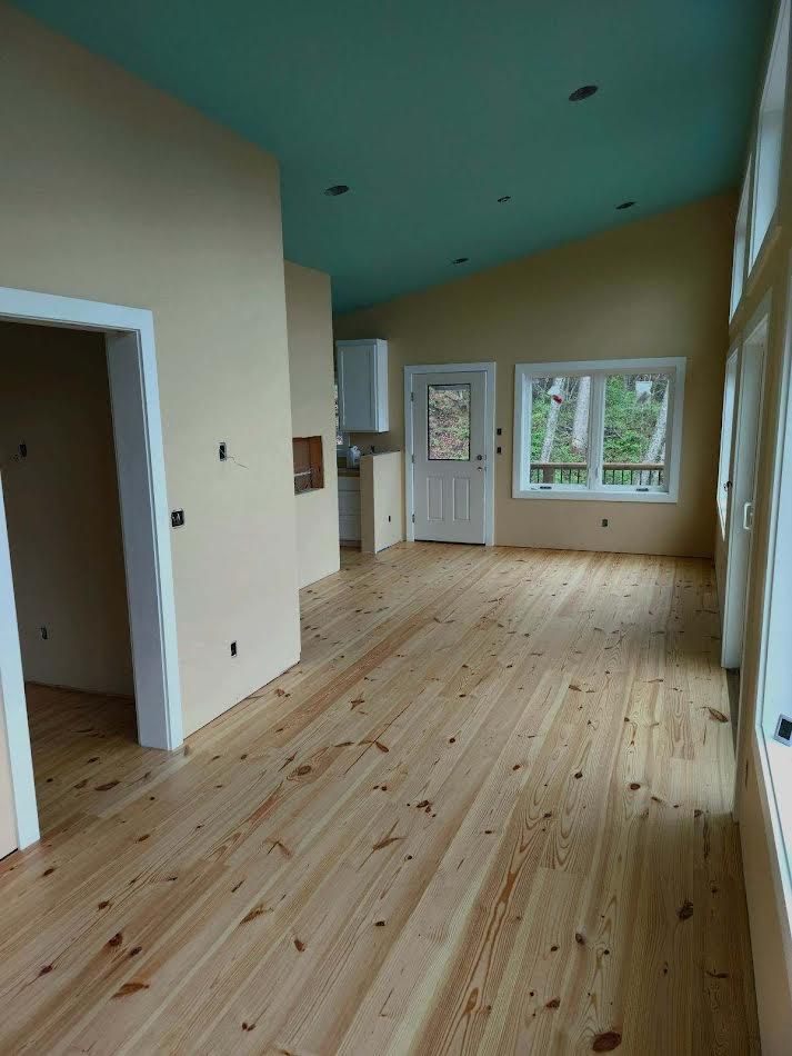 Empty room with light wood floors, pale yellow walls, and a turquoise ceiling.