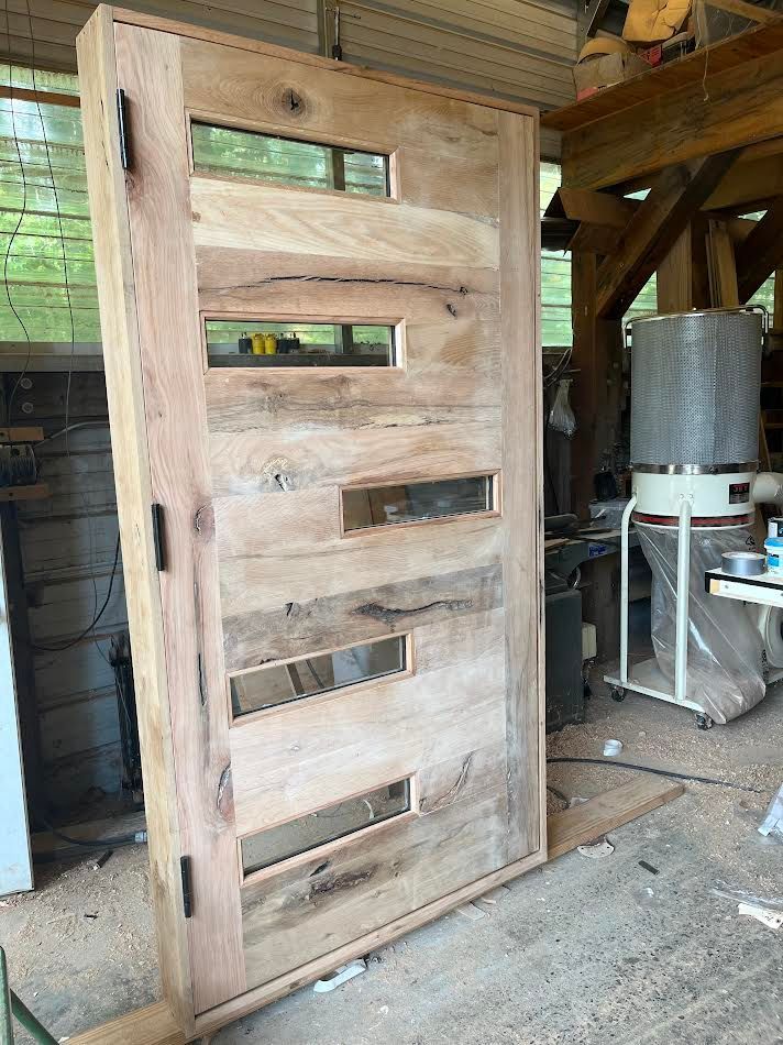 Wooden door with rectangular glass panes, resting in a workshop.