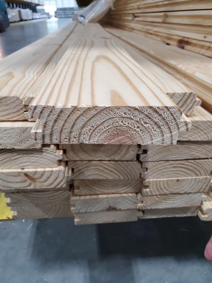 Close-up of a stack of wooden planks. The planks have a tongue and groove design, showing wood grain.