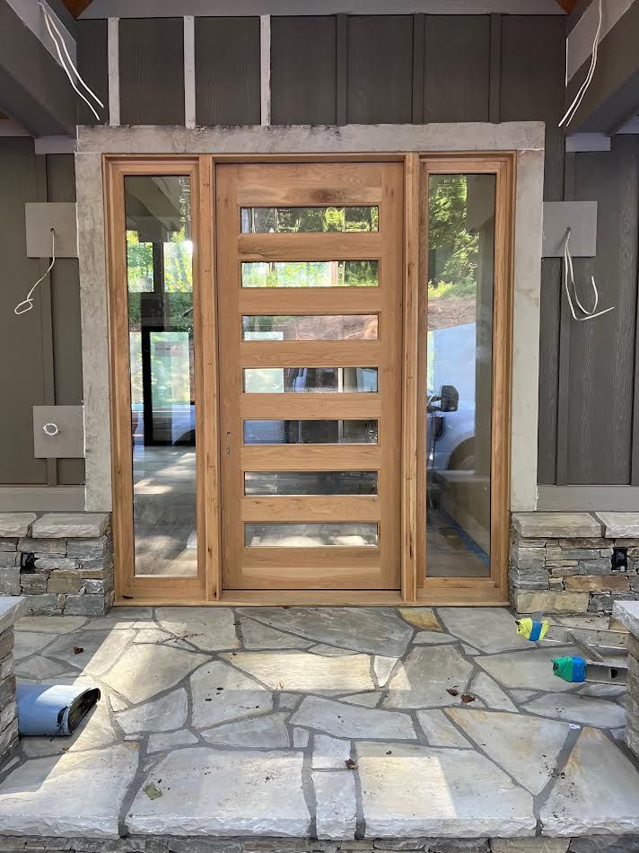Wooden door with glass panes and sidelights on a stone patio.
