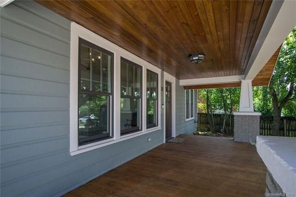 Porch exterior with wooden ceiling and flooring, blue siding, and white window frames.