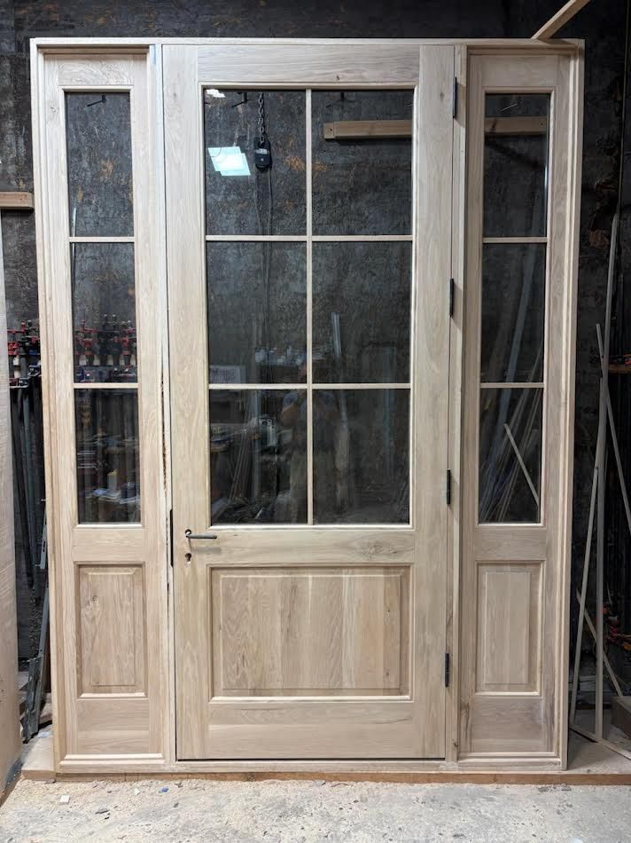 Wooden door with sidelights, featuring clear glass panes and an unfinished, light wood grain.