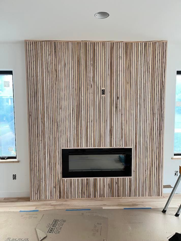 Fireplace with vertical wood paneling and a black fireplace insert.
