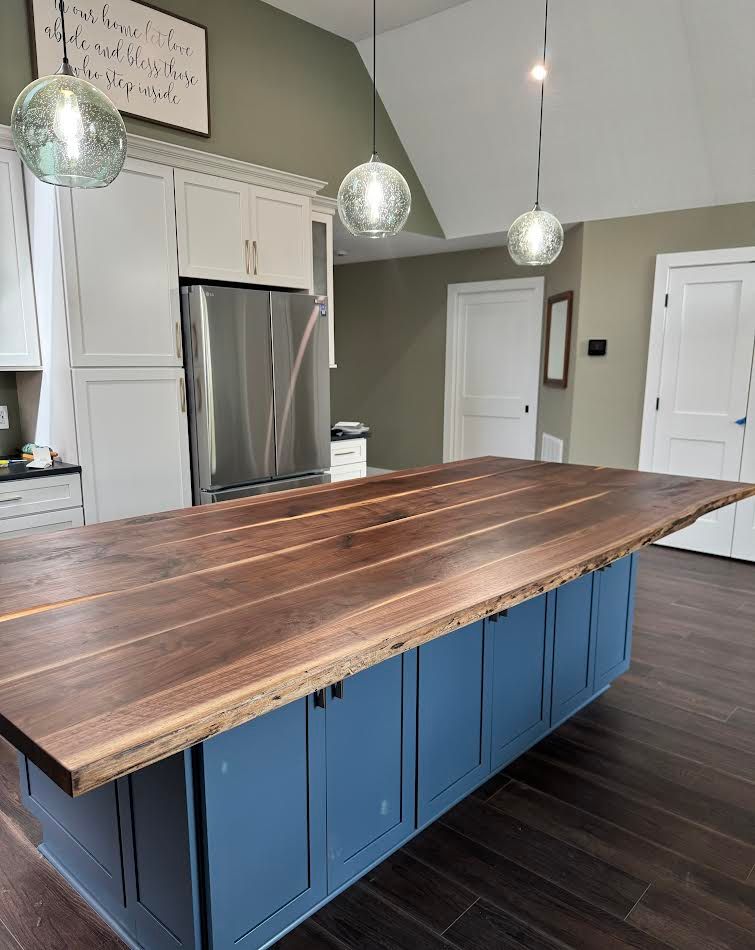Kitchen island with a wooden countertop and blue cabinets, beneath hanging globe lights.