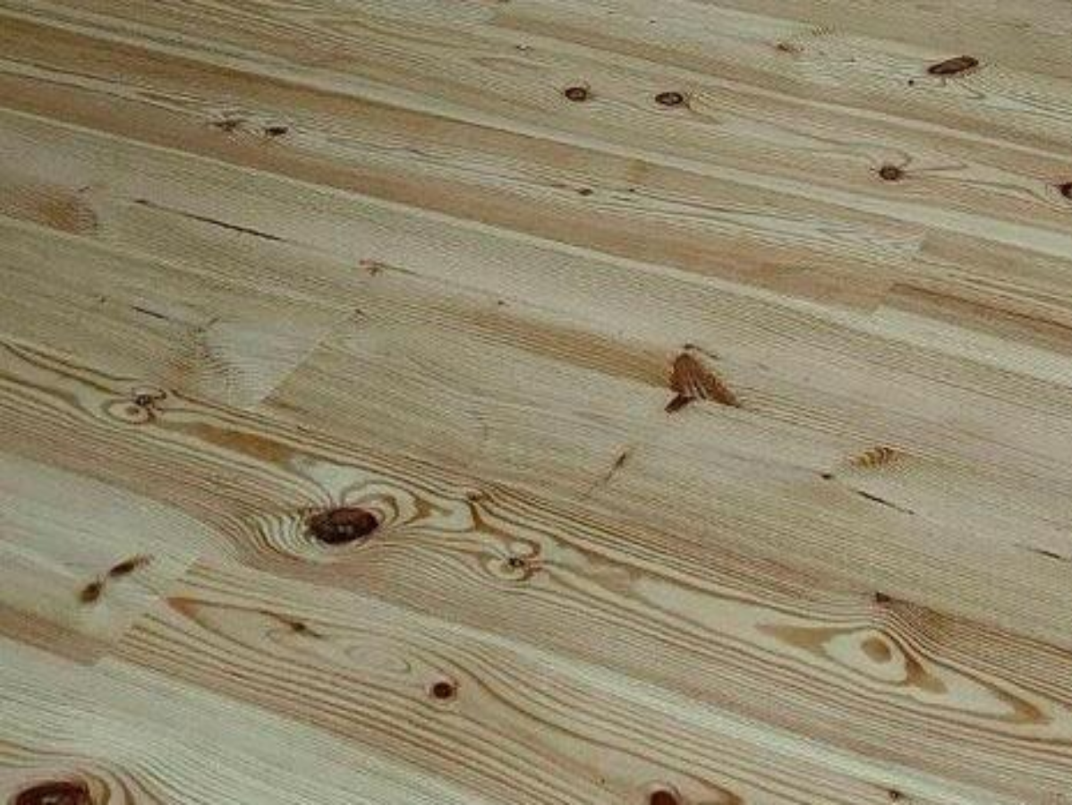 Light-colored wooden floorboards, diagonal perspective, showing wood grain and knots.