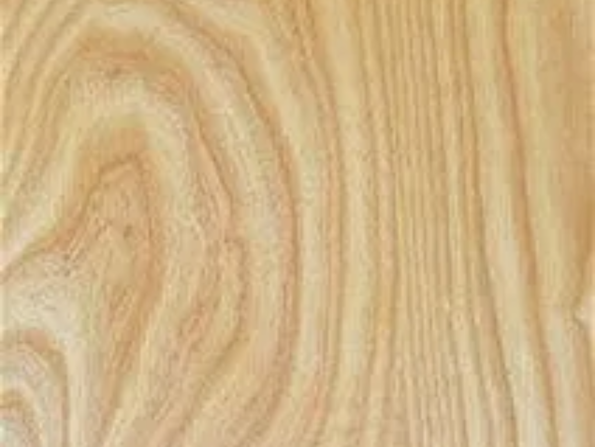 Close-up of light-colored wood grain with swirling and linear patterns, showing annual growth rings.