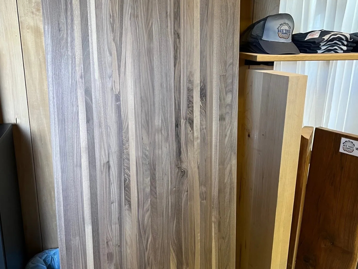 Wooden planks stacked in a retail setting, showcasing grain patterns and varying shades of brown.