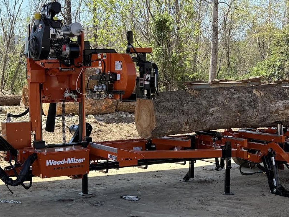 Orange Wood-Mizer sawmill cutting a large log outdoors.