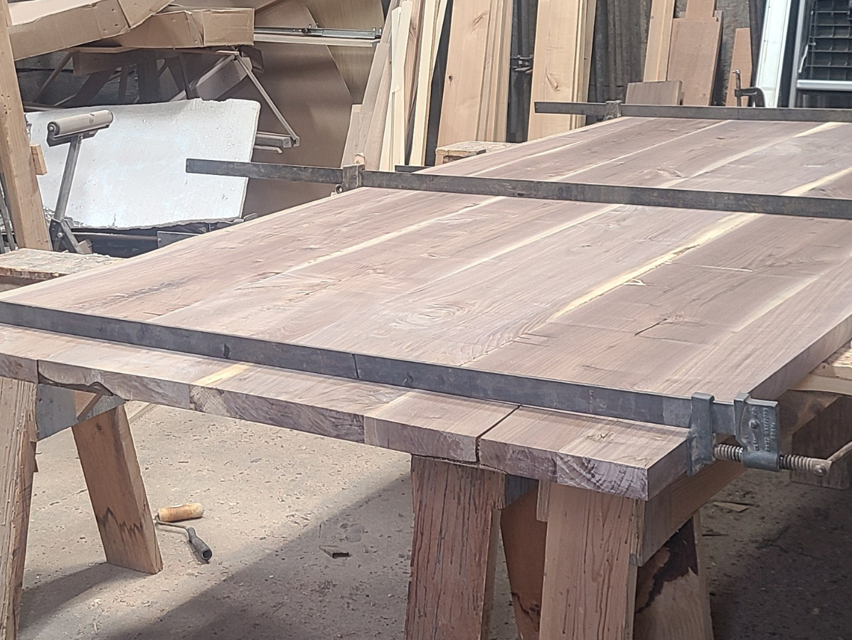 Wood planks clamped together on a workbench; woodworking project.