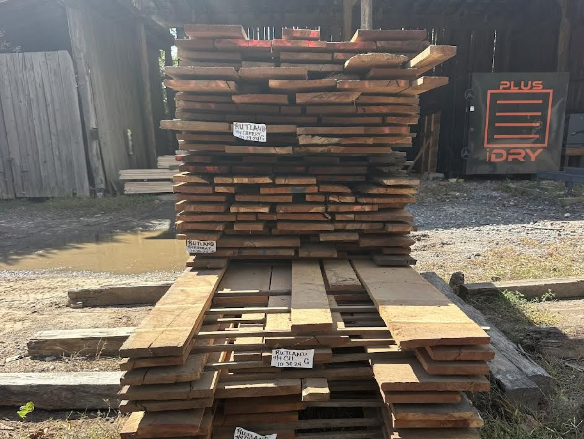 Stack of brown lumber, outside, with a 