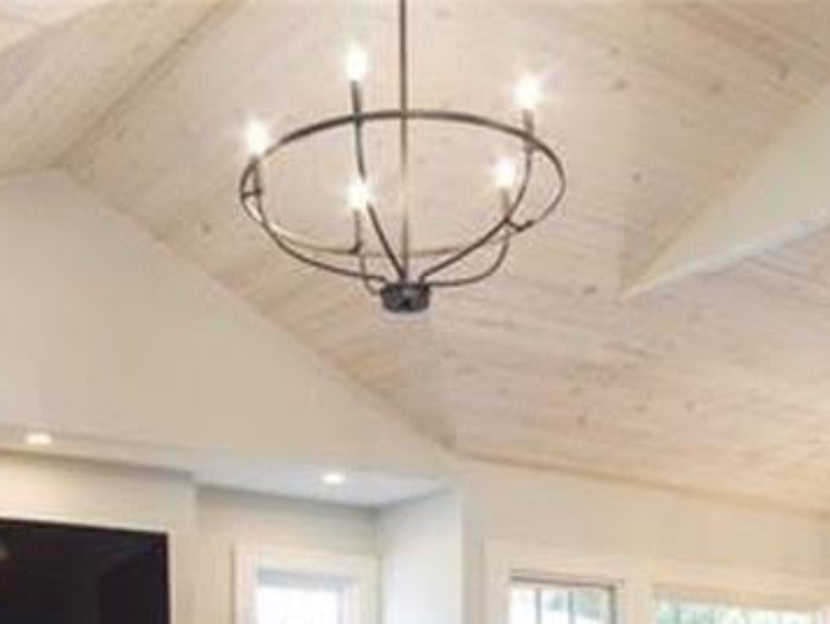 Chandelier hanging from a white, wooden-planked ceiling.